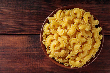 Raw Creste di Gallo Pasta in Clay Bowl on Wooden Boards, Top View, Copy Space