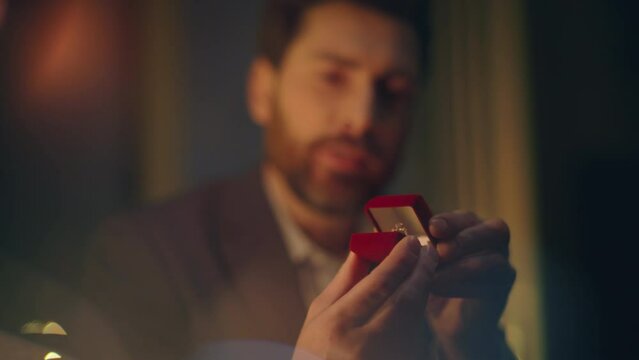 Handsome man making proposal to woman at night date closeup. Macho opening box