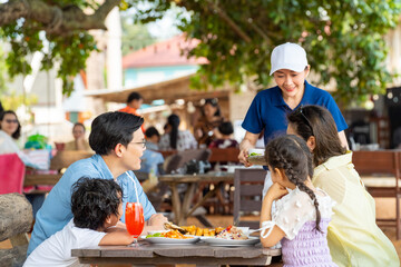 Happy Asian family parents and child kids having lunch together at beach restaurant while travel at...