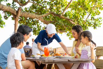 Happy Asian family parents and child kids having lunch together at beach restaurant while travel at...