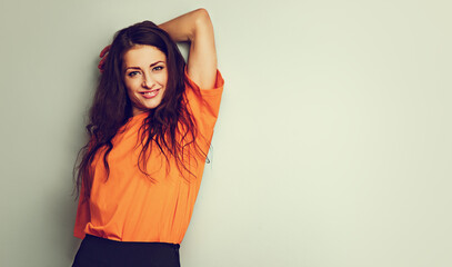 Beautiful relaxing happy casual woman in bright orange t-shirt looking on blue studio background on...