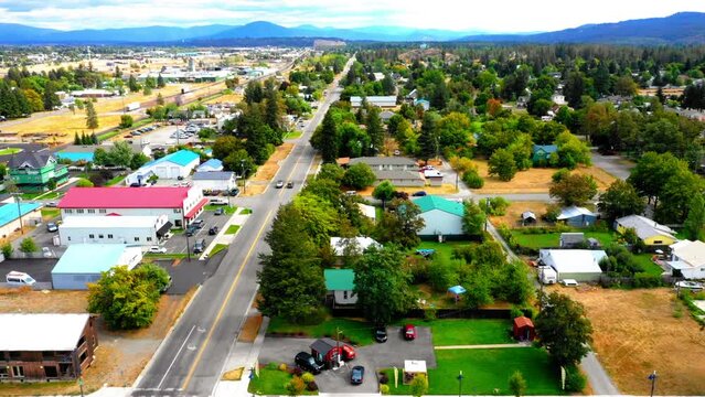 Aerial Panning Tilt Up Scenic View Of Houses Amidst Green Trees On Residential Town Landscape By Mountains - Coeur d'Alene, Idaho