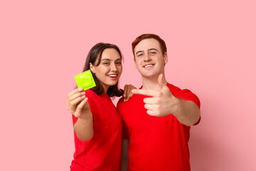 Young couple with condom on pink background. Safe sex concept