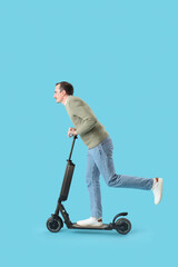Young man with kick scooter on blue background © Pixel-Shot
