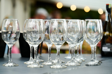 empty wine glasses stand in a row on the table. blurred background. A garland shines in the...