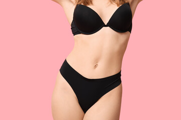 Attractive young woman in black underwear on pink background, closeup