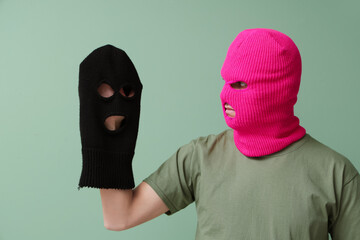 Handsome young man with balaclavas on green background
