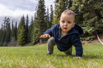 Baby boy playing outside on green grass in lush Canadian Nature.