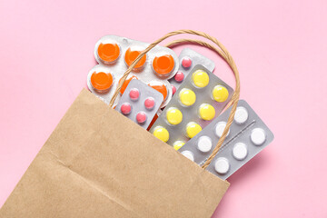 Shopping bag with different pills in blister packs on pink background