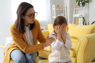 Female psychologist working with crying little girl in office