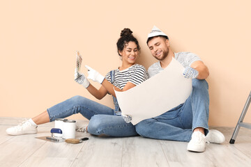 Beautiful young couple with color palette near beige wall doing repair in new house