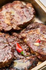 The ruddy texture of juicy Black Angus steaks cooked on the grill is covered in a butter sauce with spices and chili pepper. Close-up