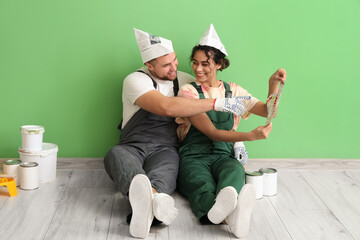 Beautiful young couple with paint cans choosing color of wall while doing repair in new house