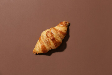 Tasty croissant on brown background