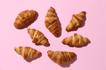 Many tasty croissants on pink background
