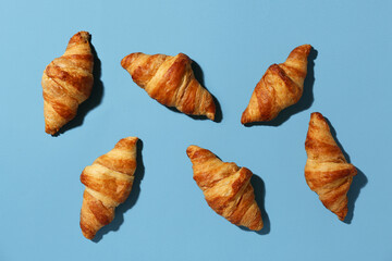 Fototapeta premium Many tasty croissants on blue background