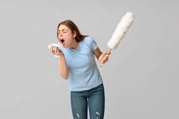 Coughing young woman with pp-duster on grey background