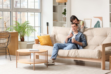Fototapeta premium Young couple in love with cups of coffee at home