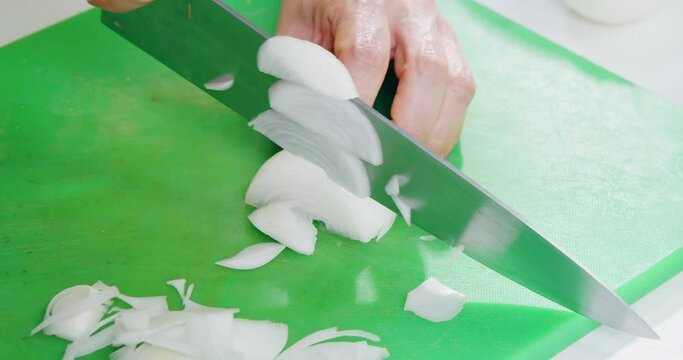 Close up of hands cutting onion into thin slices.