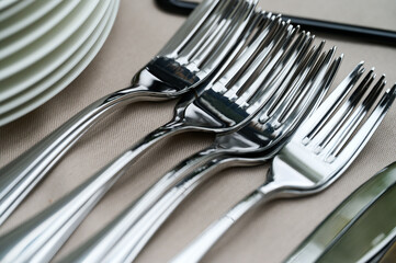 clean tableware is stacked on the table. Forks, plates, knives, cutlery on a table covered with a...