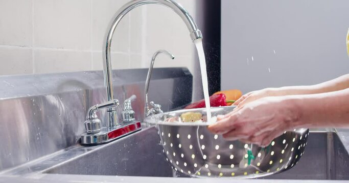 Chef washing vegetables with water responsibly.