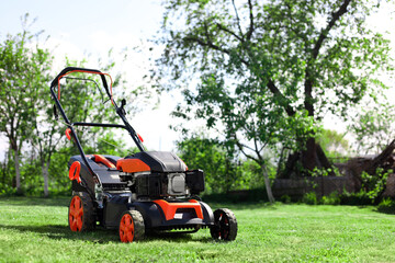 Obraz premium Modern lawn mower on green grass in garden