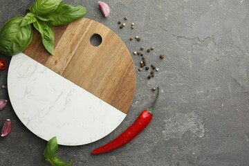 Cutting board, basil, pepper, chili peppers and garlic on grey table, flat lay. Space for text