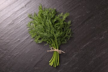 Bunch of fresh dill on dark textured table, top view