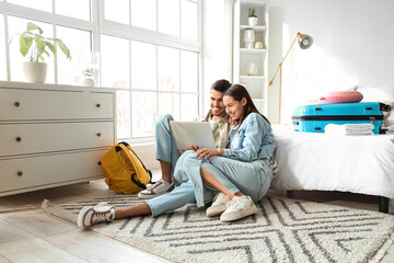 Young couple of tourists using laptop in hotel room