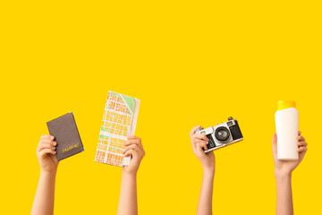 Female hands with passport, map, photo camera and sunscreen on yellow background. Travel concept.