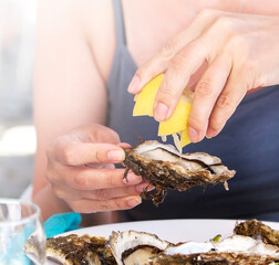 Woman eat oysters with lemon. Soft sunlight © bborriss