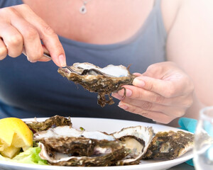 Woman eat oysters with lemon. Soft sunlight