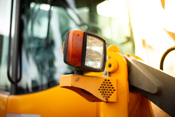 Headlights of a yellow excavator, close-up. Working site, nobody.
