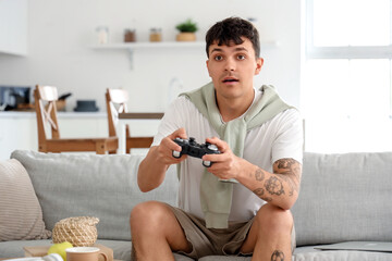 Young man playing video game on sofa at home
