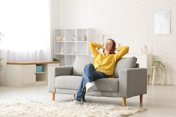 Young happy woman resting on sofa in living room