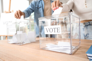 Voting people near ballot boxes at polling station, closeup