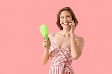 Young woman with mini green electric fan using mobile phone on pink background