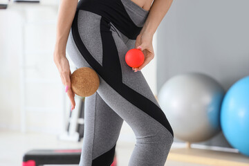 Sporty young woman with massage balls at gym, closeup