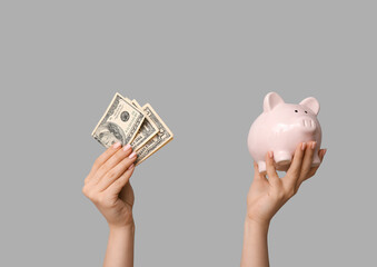 Female hands with money and piggy bank on grey background