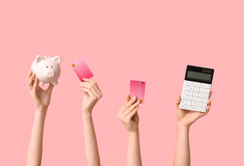 Fototapeta premium Female hands with credit cards, calculator and piggy bank on pink background
