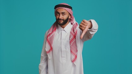 Islamic adult gives thumbs down and feeling disappointed about something, indicating muslim culture...