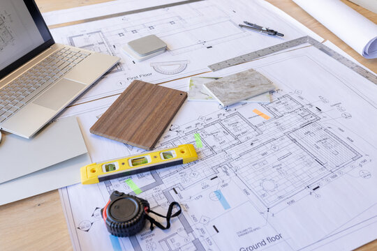 Architectural plans and tools spread out on desk, showing detailed building layouts