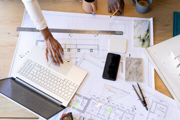 Diverse team working on architectural plans at desk with various tools