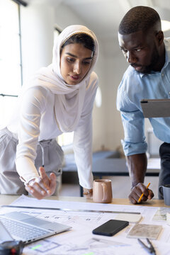 At modern office, diverse team working on architectural plans
