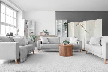 Interior of living room with grey sofas, table and shelf units