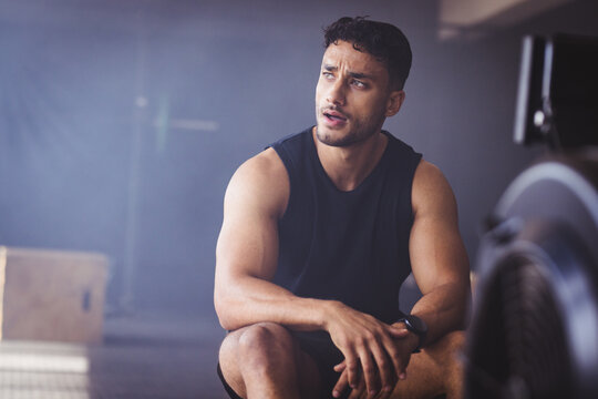Strong and fit biracial man at gym resting after intense workout session, copy space