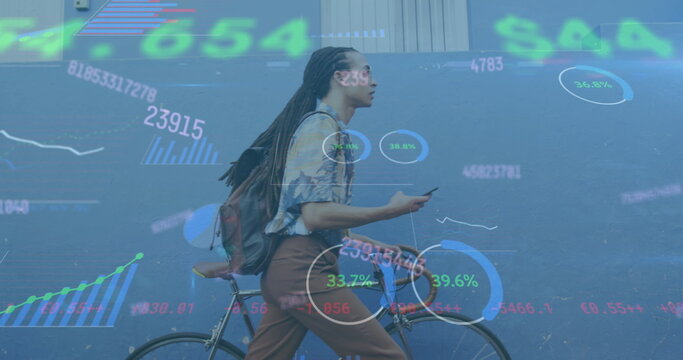 Image of graphs, numbers, trading board, biracial man walking with bicycle and using cellphone