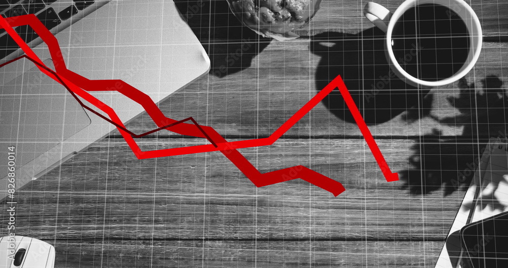 Poster red line graph displaying decline, covering a desk with a laptop and coffee
