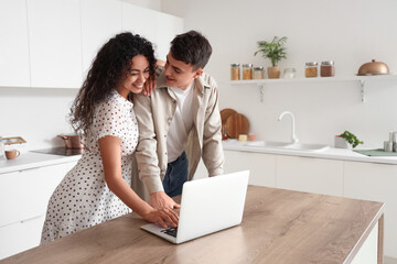 Young loving couple using laptop in kitchen
