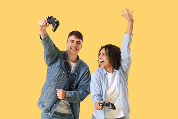 Young couple in love playing video game on yellow background